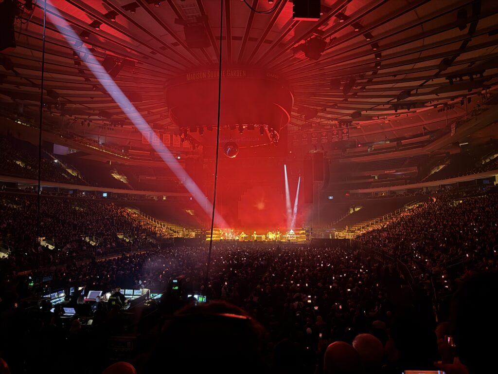 The stage at MSG. Bathed in red light. Four female singers stage left, the bassist next. Gilmour next. Behind him the drummer. To the right the keyboardist and percussion.