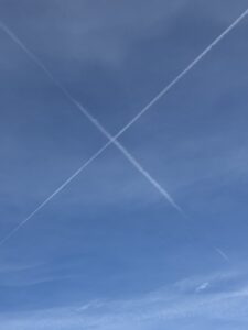 x marks the spot. trails form tow aircraft criss crossing in the sky.