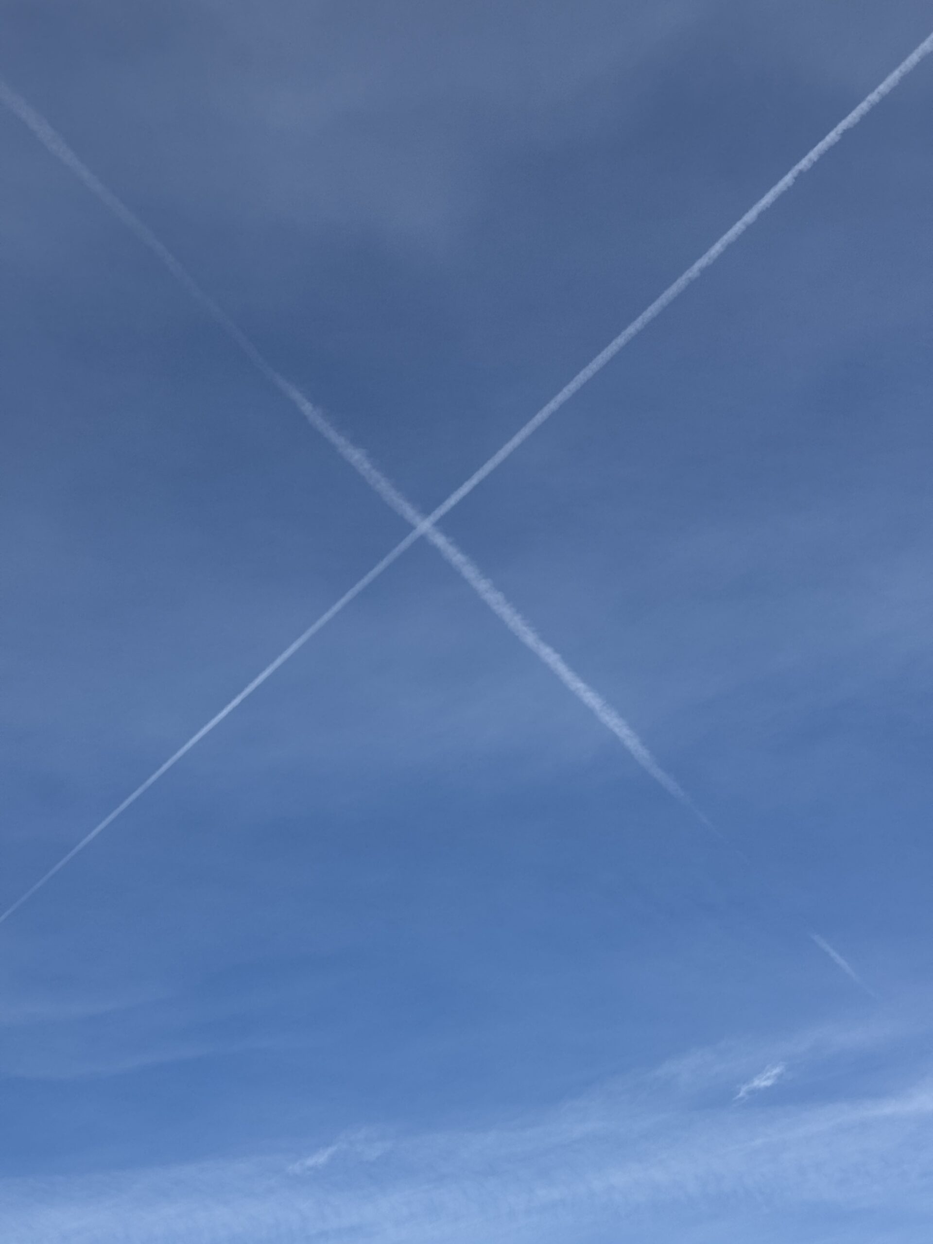 x marks the spot. trails form tow aircraft criss crossing in the sky.